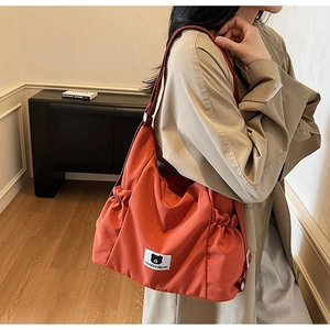 Detail of caramel canvas shoulder bag showing drawstring side and cute bear patch