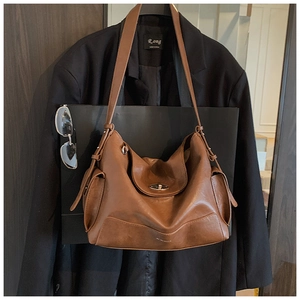 Detail of a brown leather tote bag showing vintage swivel clasp and side pocket texture