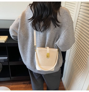 Detail of cream bucket bag with gold clasp and textured leather shown on model