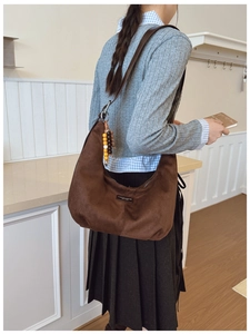 Brown suede slouchy shoulder bag detail with leather logo patch and colorful bead charm