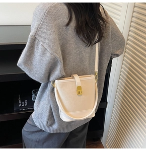 Detail view of cream leather bucket bag with gold twist lock and shoulder strap