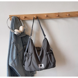 Detail of grey canvas messenger bag with adjustable strap and side drawstring pocket