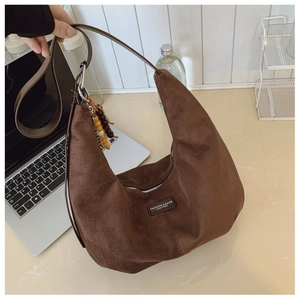 Detail view of large dark brown suede hobo bag with fashion leather tag and bead charm