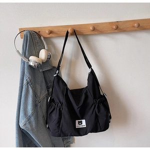 Close-up of a black canvas bag with drawstring side pockets and a cute bear label