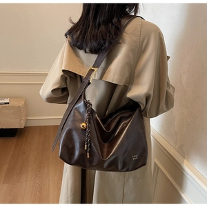 Detail of dark coffee leather tote bag with gold buckle and brand logo on shoulder strap