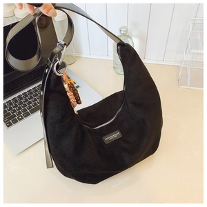 Detail of black suede hobo bag with wooden beads and woven tassel ornament on the strap