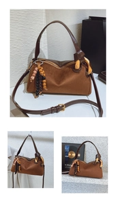 Détail du sac baguette en daim marron avec boucle dorée et breloque en perles rétro