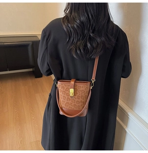 Close-up of leopard print bucket bag featuring premium brown leather and gold metal lock