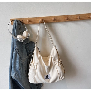 Detailed shot of the side drawstring pocket on a beige canvas shoulder bag