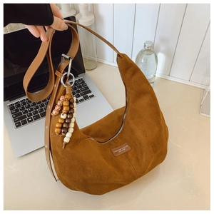 Detail of a brown suede hobo bag with wood bead tassel and silver hardware buckle