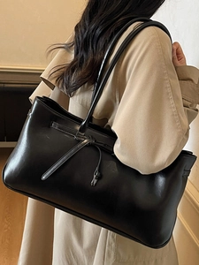 Minimalist black leather tote bag with long knotted strap detail for autumn 2025 fashion