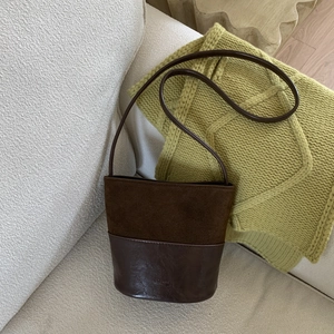 Dettaglio della borsa a secchiello vintage in pelle scamosciata marrone su coperta