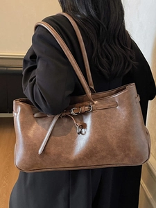 Brown leather tote bag with long handles and decorative buckle for stylish daily use