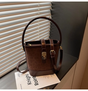 Detailed view of dark brown bucket bag with leopard print suede and gold hardware