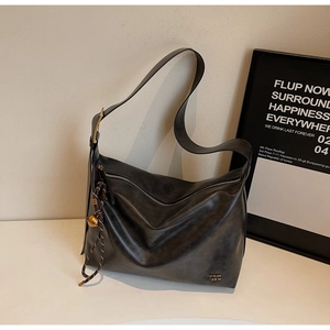 Detail view of a black Hobo shoulder bag with metallic buckle and woven rope accessory