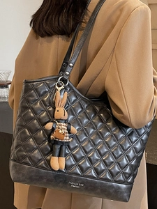 Quilted black leather tote bag with a cute rabbit charm shown on a female model