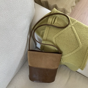 Dettaglio delle cuciture a contrasto e texture bicolore sulla borsa a secchiello in pelle