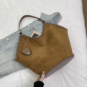 Vue de dessus du sac cabas en daim marron avec anses en cuir sur une veste en jean