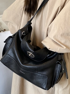Black large capacity faux leather hobo bag with silver buckle worn with beige coat