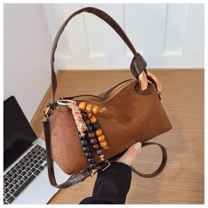 Détail d'un sac cylindrique en daim marron avec pendentif en perles de bois de style bohème