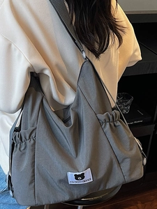 Large dark grey nylon messenger bag with bear label and functional side drawstring pockets