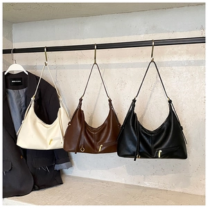 Detailed view of half-moon hobo bags in cream, brown, and black with golden metal ring