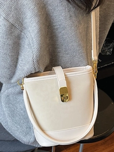 Chic cream white leather bucket tote bag with gold lock and adjustable strap on a model