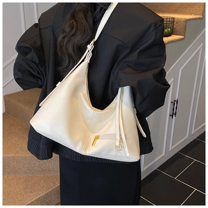 Chic cream leather hobo bag with gold zipper detail shown on a model in a stairwell
