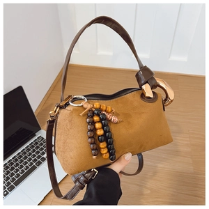Détail du sac à main en daim marron avec pendentif en bois et anneau doré élégant