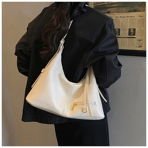 Detail of white lychee-textured hobo bag with gold hardware worn by a model in a black jacket