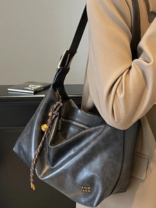 Matte black leather tote bag for women with gold logo and woven charm accessory