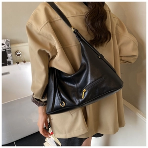 Close-up of black leather tote bag with lychee texture and gold zipper hardware