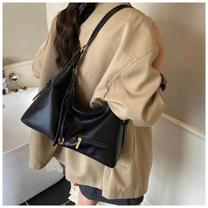 Detail view of black lychee grain leather hobo bag with gold hardware and side pocket