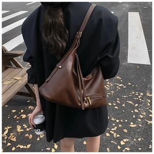 Deep brown lychee grain leather hobo bag with adjustable strap and decorative tassels