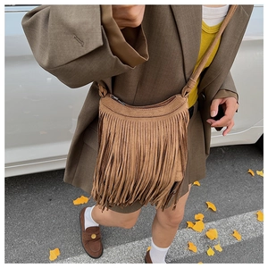 Sac bandoulière marron à franges en daim montrant un style bohème rétro en extérieur