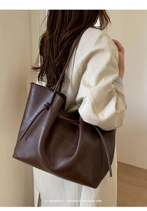 Detail showing deep brown faux leather tote texture with unique knotted drawstring design