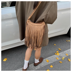 Détail d'un sac bandoulière en daim marron avec de longues franges et une lanière