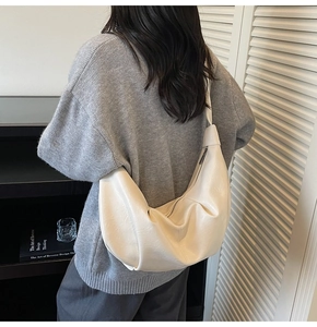 Macro detail of creamy beige pleated leather hobo bag with wide strap and zipper closure