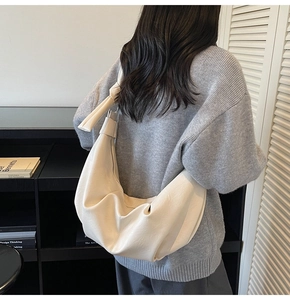 Detail shot of a cream-white soft leather dumpling bag with a unique knot shoulder strap