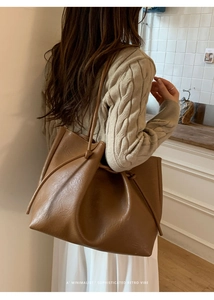 Detail of a large brown tote bag with drawstring knots shown on a shoulder strap