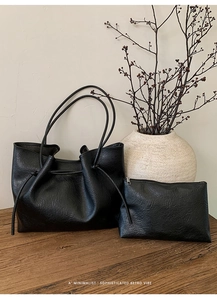Detail of minimalist black tote bag set with textured leather and drawstring closure