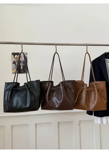 Detail view of large tote bags in three colors hanging on a metal bar with knotted straps