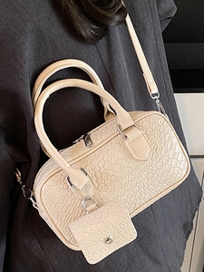 Cream woven texture Boston crossbody bag with mini pouch charm shown on shoulder