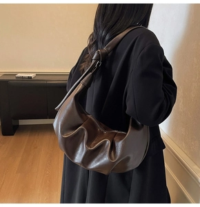 Detail of dark brown hobo bag featuring soft pleated leather and knotted shoulder strap