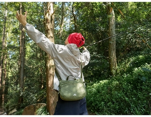 Outdoor crossbody bag in green plaid nylon shown during a forest hiking trip