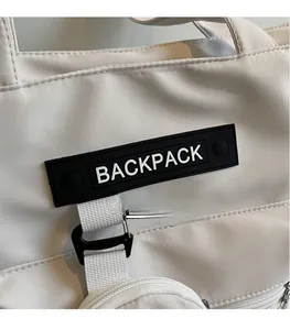 Détail de sac à dos en toile beige avec logo noir et bandoulière tissée résistante