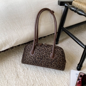 Détail du sac Boston léopard avec poignées en cuir synthétique sur tapis blanc