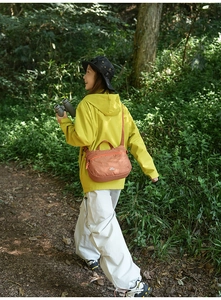 Outdoor brick red grid crossbody bag detail worn by a model in a forest setting