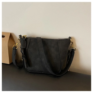 Close-up of matte black shell bag with gold hardware and leather tassel detail