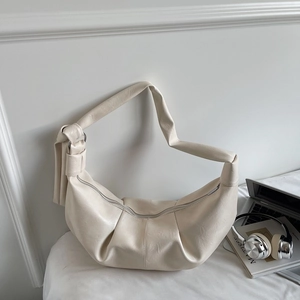 Detail of soft cream pleated moon bag with wide shoulder strap and textured leather finish